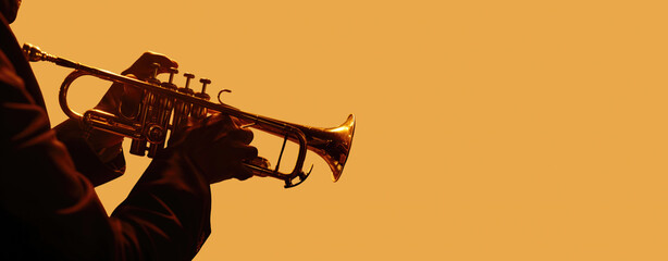 Silhouette of a musician playing a trumpet against a vibrant orange backdrop