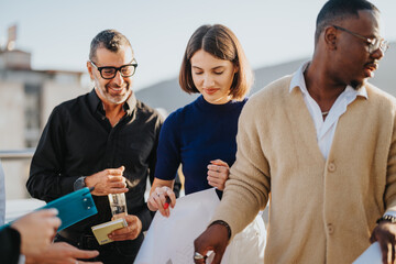 A diverse group of business people collaborate on a high-rise balcony during sunset. They are...