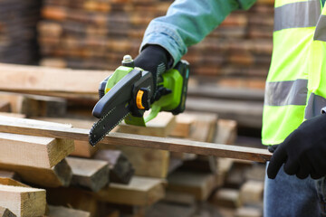 Male carpenter sawing plank at sawmill, closeup