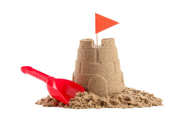 Castle made of sand with red flag and toy shovel on white background