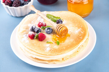 Traditional Maslenitsa food, Eastern European Slavic thin pancakes crepes, with various sweet spreads, toppings and fillings - honey, berries, jams 