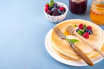 Traditional Maslenitsa food, Eastern European Slavic thin pancakes crepes, with various sweet spreads, toppings and fillings - honey, berries, jams 
