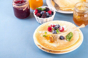 Traditional Maslenitsa food, Eastern European Slavic thin pancakes crepes, with various sweet spreads, toppings and fillings - honey, berries, jams 