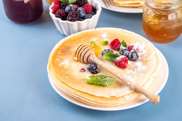 Traditional Maslenitsa food, Eastern European Slavic thin pancakes crepes, with various sweet spreads, toppings and fillings - honey, berries, jams 