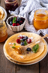 Traditional Maslenitsa food, Eastern European Slavic thin pancakes crepes, with various sweet spreads, toppings and fillings - honey, berries, jams 