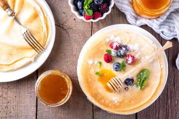 Traditional Maslenitsa food, Eastern European Slavic thin pancakes crepes, with various sweet spreads, toppings and fillings - honey, berries, jams 