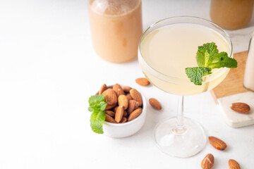 Sweet and sour lemon orgeat cocktail, Orgeat Lemonade Recipe, one martini glass with alcohol boozy drink and almond orgeat syrup bottle