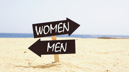 Arrows on the beach pointing two opposite directions towards Men and Women