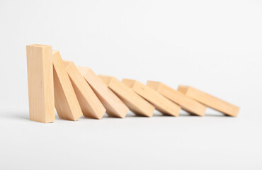 Domino effect. Wooden blocks falling on light background