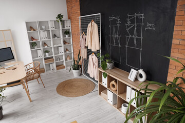 Interior of clothing store office with workplace, shelving units and stylish clothes