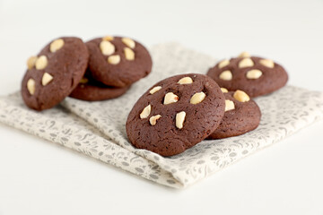 Tasty chocolate cookies with hazelnuts on white table, closeup