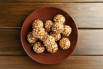 Delicious chocolate puffed rice balls in bowl on wooden table, top view