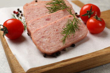 Pieces of tasty canned meat, dill, peppercorns and tomatoes on grey table, closeup