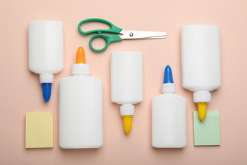 Bottles of glue, scissors and notes on beige background, flat lay