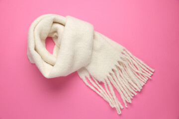 Warm woolen scarf on pink background, top view