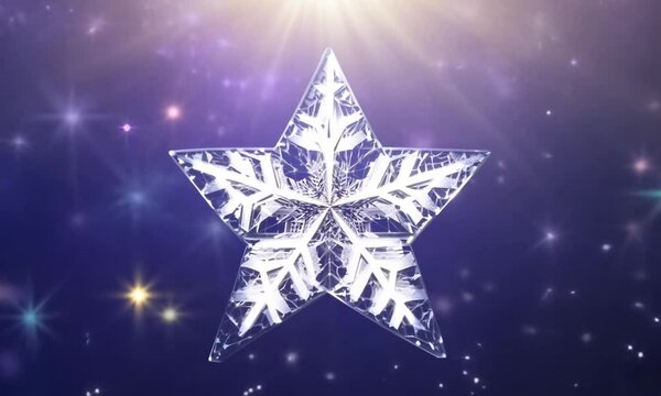 A snowflake is shown in close-up against a blurry background of other snowflakes and a bright light. The snowflake has a complex, intricate structure, and the light makes it sparkle and shim