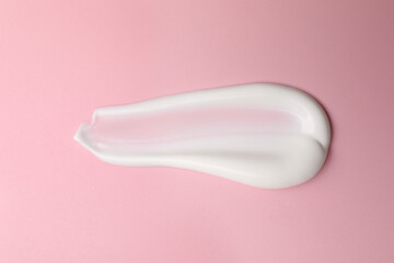 Cream on pink background, top view. Sample of cosmetic product