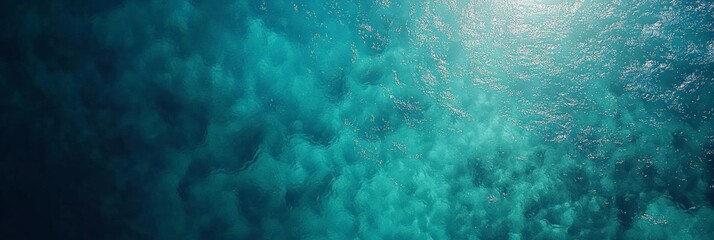 Obraz premium Aerial view of calm ocean water surface with sun reflecting and creating beautiful turquoise patterns, ideal for summer and travel themes, showcasing the beauty of nature and tropical destinations