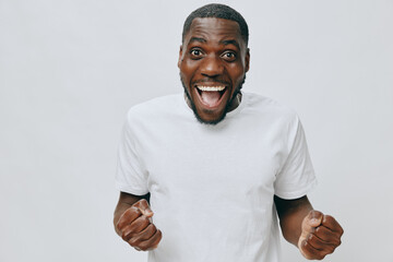Happy cheerful man celebrating success, smiling broadly, wearing a plain white t shirt, with a...
