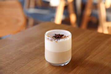 Glass of aromatic coffee on wooden table in cafe, closeup