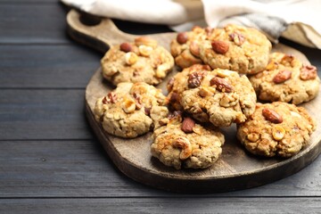 Tasty cookies with nuts on dark wooden table, closeup