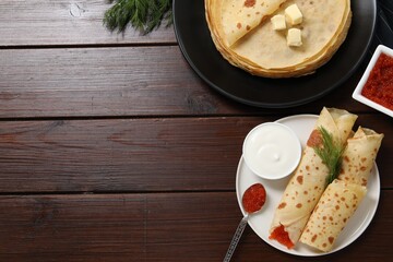 Delicious crepes with red caviar served on wooden table, flat lay. Space for text