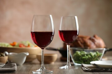 Red wine and delicious dinner served on wooden table, closeup