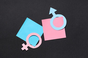 Female and male paper gender symbols with stickers on black background