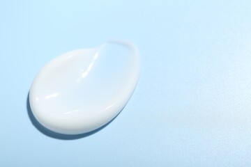 Cream sample on light blue background, closeup. Space for text