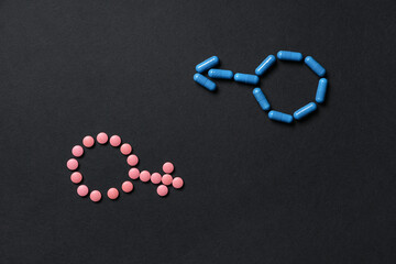 Male and female gender symbols made of pills on black background