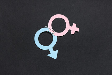 Male and female gender symbols with paper clip on black background