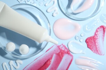 Cream, scrub and gel samples on light blue background, flat lay. Stylish presentation with tube of skincare product