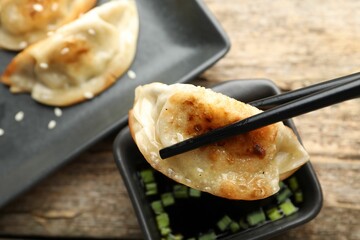 Eating fried gyoza dumplings at wooden table, closeup