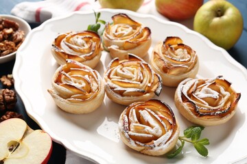 Tasty apple roses with powdered sugar served on table, closeup
