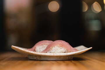 Exquisite hamachi nigiri sushi on a ceramic plate, featuring delicate yellowtail slices over seasoned rice.