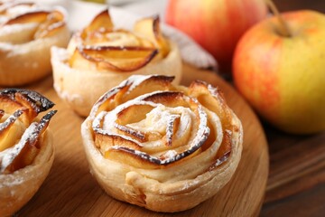 Freshly baked apple roses and fruits on table, closeup