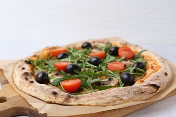 Tasty pizza with cherry tomatoes, black olives, mushrooms and arugula on white table, closeup