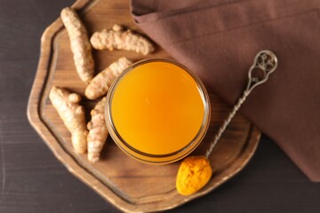 Aromatic turmeric tea in glass, roots and powder on wooden table, top view