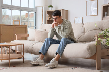 Worried young man sitting on sofa  at home