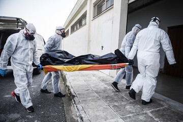 Funeral Home employees wear protective suits to protect themselves from Coronavirus, as they carry...