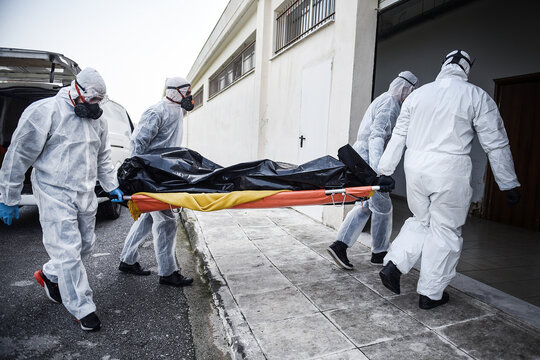 Funeral Home employees wear protective suits to protect themselves from Coronavirus, as they carry a dead body inside a Bag.