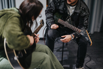 Two people playing guitars in a music studio, engaged in a collaborative rehearsal, possibly preparing new music or practicing for a performance.