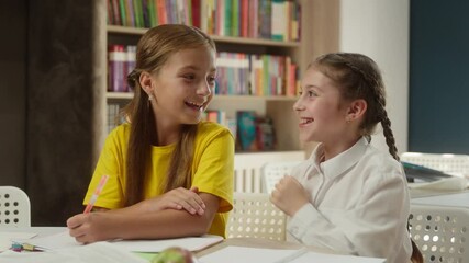 Caucasian little funny kids children friends talking in school classroom studying together laughing girls tell secret whisper gossip have fun conversation schoolgirls pupils students education indoors - Powered by Adobe