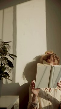Young woman reading a book, faceless aesthetic background video, warm and dreamy cinematic feeling