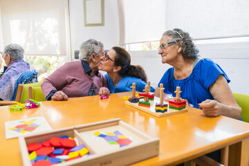 Fototapeta premium Nurse kissing elderly woman in geriatric nursing home during recreational activity