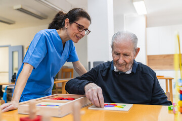 Nurse assisting elderly man playing with puzzle in nursing home