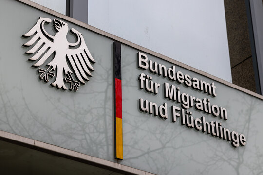 Nahaufnahme des Logos und der Beschriftung des Bundesamts f&uuml;r Migration und Fl&uuml;chtlinge (BAMF) an der Fassade des Geb&auml;udes. 