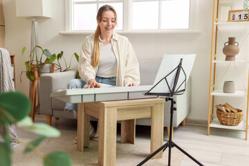 Young woman playing synthesizer at home