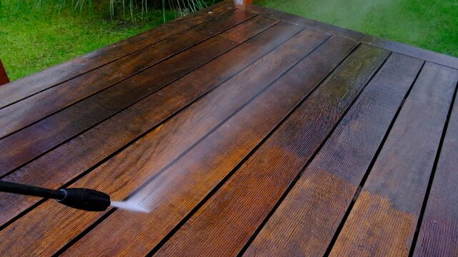 cleaning terrace with a power washer - high water pressure cleaner on wooden terrace surface - 4K video