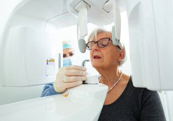 Dentist preparing elderly woman for dental panoramic radiograph